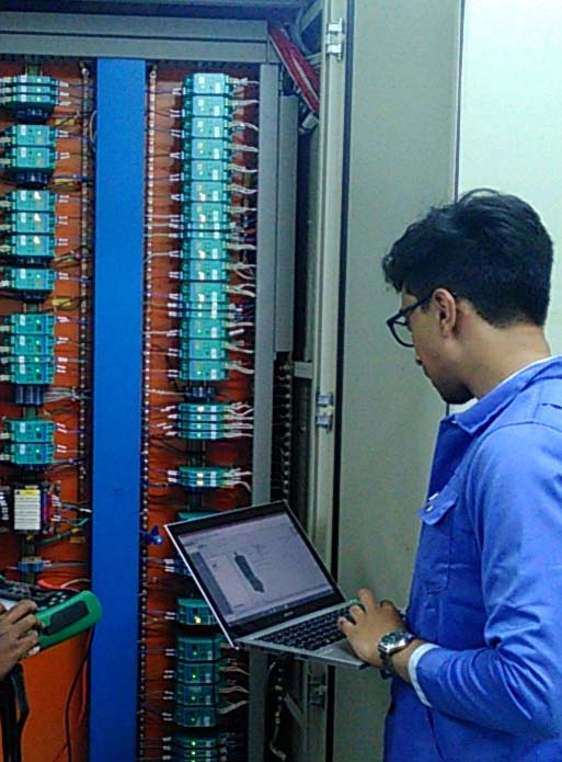 A SECL engineer at an open marshalling cabinet, laptop connected, checking terminations