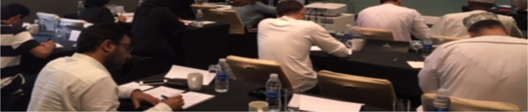 A SECL course in session: delegates at tables facing a projected critical-path analysis slide
